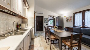 Una cocina moderna con horno empotrado, un comedor con mesa y sillas de madera, y un sofá en la sala de estar.