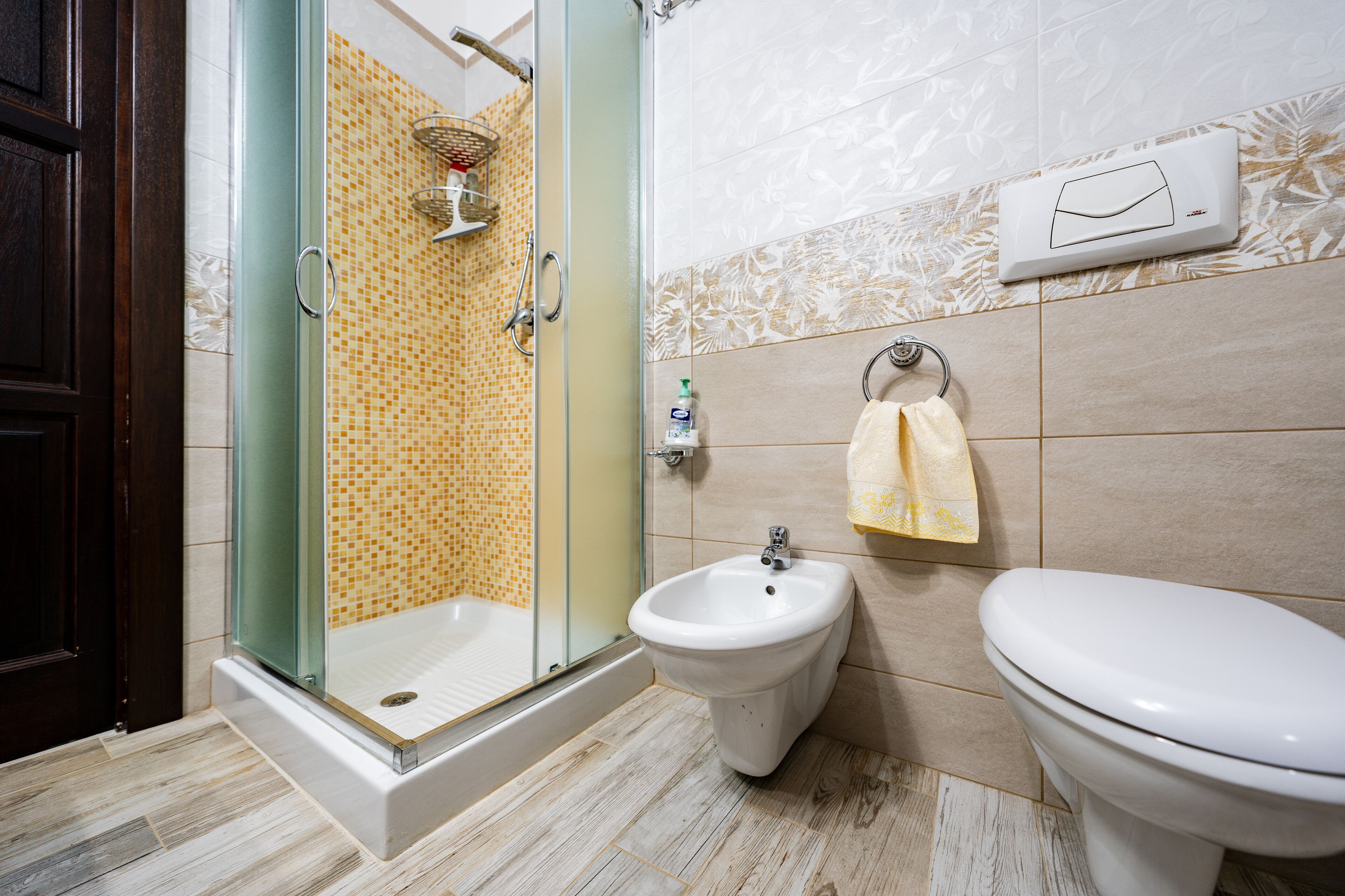 A bathroom with a glass-enclosed shower, a bidet, and a toilet.