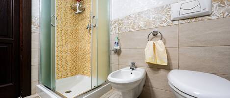 A bathroom with a glass-enclosed shower, a bidet, and a toilet.