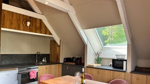 Eine moderne Küche mit Holzschränken, einem eingebauten Ofen und einem Essbereich mit einem Holztisch und rosafarbenen Stühlen.