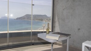 Une chambre moderne dotée d’une grande fenêtre donnant sur une vue panoramique de la côte.