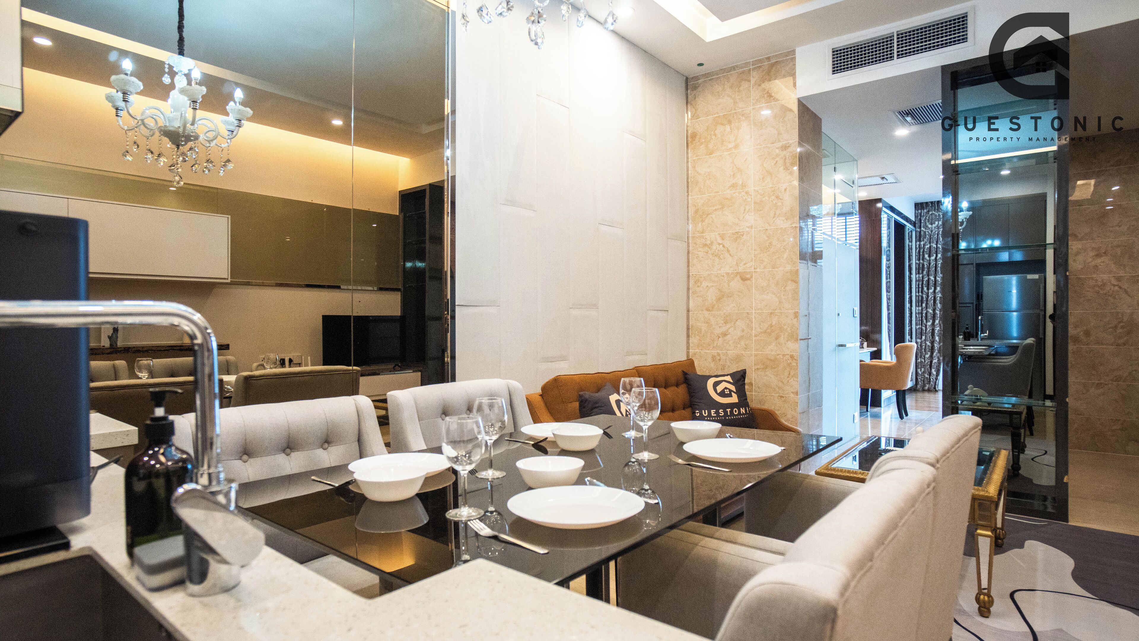Ein moderner Essbereich mit Glastrennwand, einer Chandelierleuchtre und Blick auf ein Immobilienbüro.