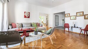 A modern living room with a sofa, chairs, a coffee table, and a dining area with a table and chairs. - Artsi - 3BR Apt w Balcony in Athens (Athens)