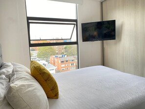 Une chambre d’hôtel avec un lit, une fenêtre et un téléviseur fixé au mur.