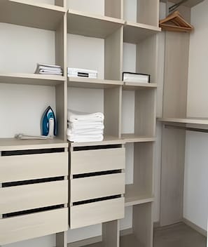 A closet with multiple shelves and drawers, containing folded towels and a blue iron. - Edificio Area 93  (Bogotá)