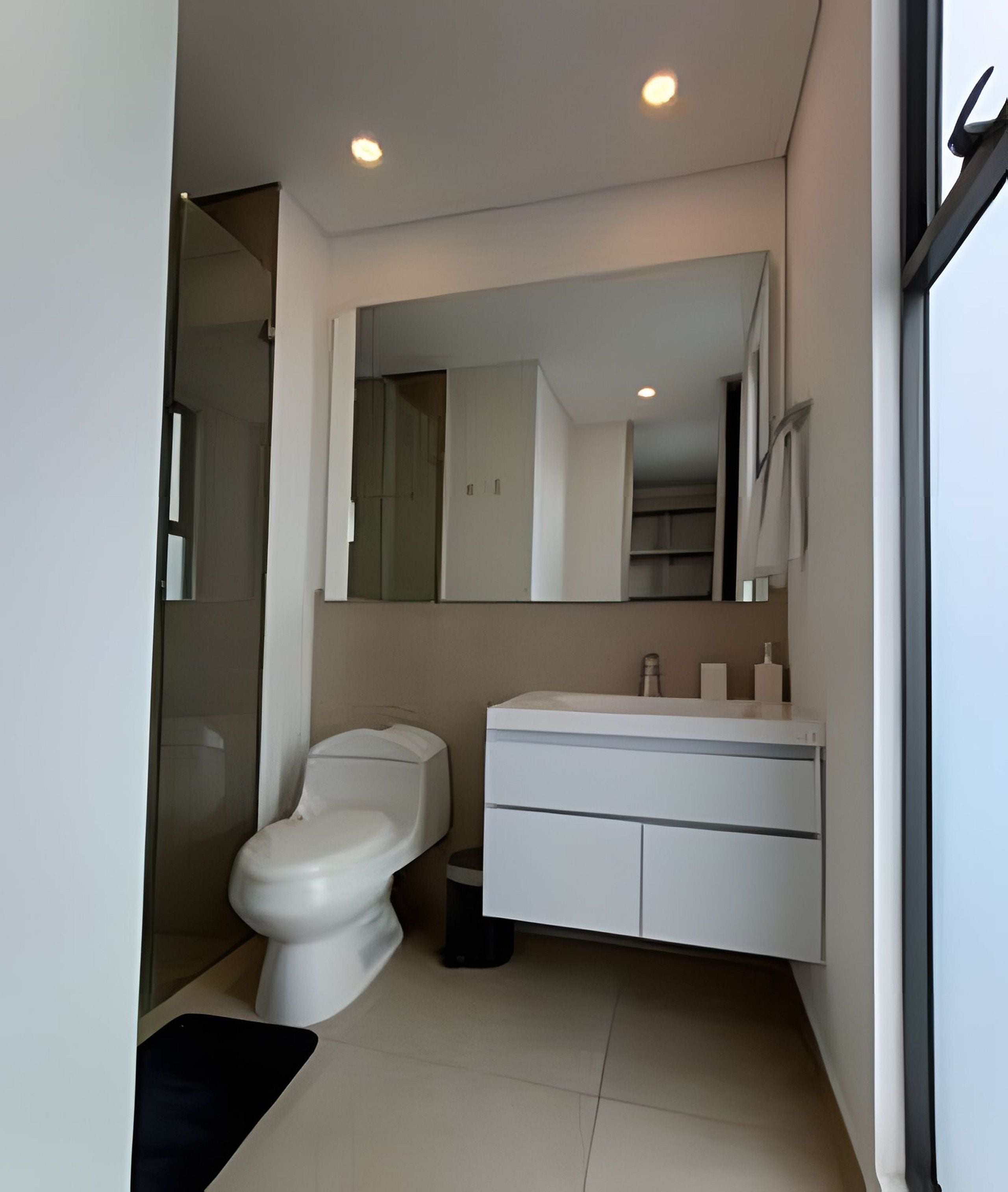 A modern bathroom with a toilet, sink, and mirror.