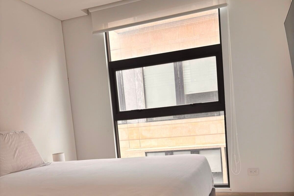 A bedroom with a bed, a window, and a view of the outside.
