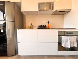 A modern kitchen with a built-in microwave, oven, and a coffee maker on the countertop. - Edificio Area 93  (Bogotá)