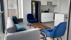 A modern kitchen with white cabinets, a stainless steel refrigerator, and a microwave. - Edificio Area 93  (Bogotá)