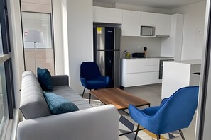 A modern kitchen with white cabinets, a stainless steel refrigerator, and a microwave.