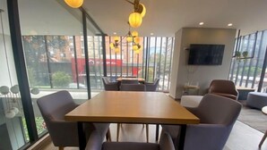 A modern conference room with a wooden table and comfortable seating. Large windows provide a view of the outside. - Edificio Area 93  (Bogotá)