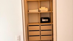 A walk-in closet with wooden shelves and drawers, a radio, and folded towels. - Edificio Area 93  (Bogotá)