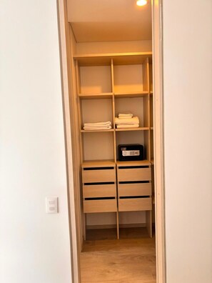 A walk-in closet with wooden shelves and drawers, a radio, and folded towels.