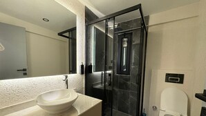 Ein modernes Badezimmer mit einem weißen Waschbecken, einer Duschkabine aus Glas und einer Toilette.