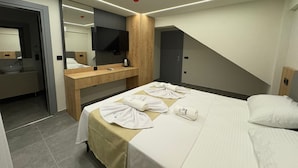 Ein modernes Hotelzimmer mit Bett, Schreibtisch, Spiegel, Fernseher und einer Tür.
