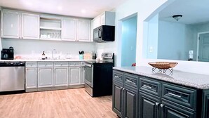 A modern kitchen with light grey cabinets, a black stove, and a large island with a woven basket. - Cozy home near Latta Nature Preserve (Huntersville)