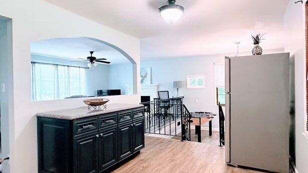 A modern kitchen with dark cabinetry, a wooden countertop, and a central island. There is a dining area with a table and chairs, and a staircase leading to another level. - Cozy home near Latta Nature Preserve (Huntersville)