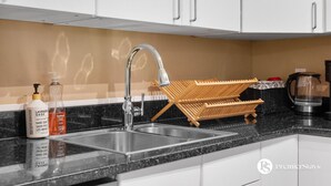 A modern kitchen with a double sink, stainless steel faucet, and a wooden drying rack. - Two Floor Apartment » Gym » Private Balcony (Calgary)
