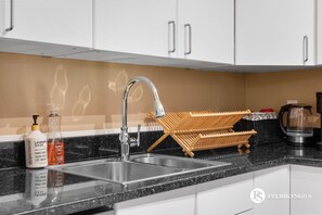 Una cocina moderna con un lavamanos doble, grifo de acero inoxidable y un tendedero de madera.