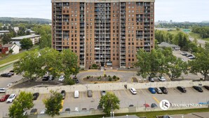 A multi-story brick building with a central courtyard and parking lot. - Two Floor Apartment » Gym » Private Balcony (Calgary)