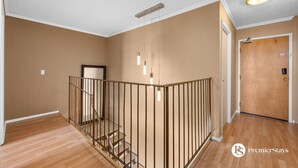 A spacious room with a wooden staircase, a door, and a light fixture on the ceiling.