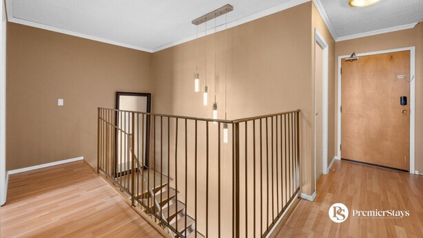 A spacious room with a wooden staircase, a door, and a light fixture on the ceiling. - Two Floor Apartment » Gym » Private Balcony (Calgary)