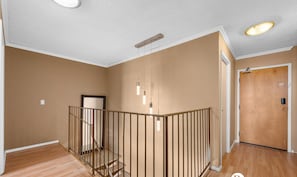 Um quarto amplo com escada de madeira, uma porta e luminária no teto.