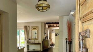 A hallway with a stone floor, a hanging light fixture, and a wooden door with a brass handle. - BASTIDE DE L'ORANGERAIE SWIMMING POOL AIR CONDITIONING (Vence)