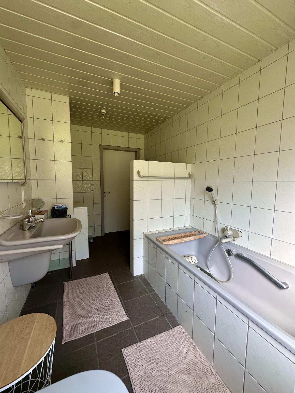 Un baño con lavamanos, espejo y bañera.