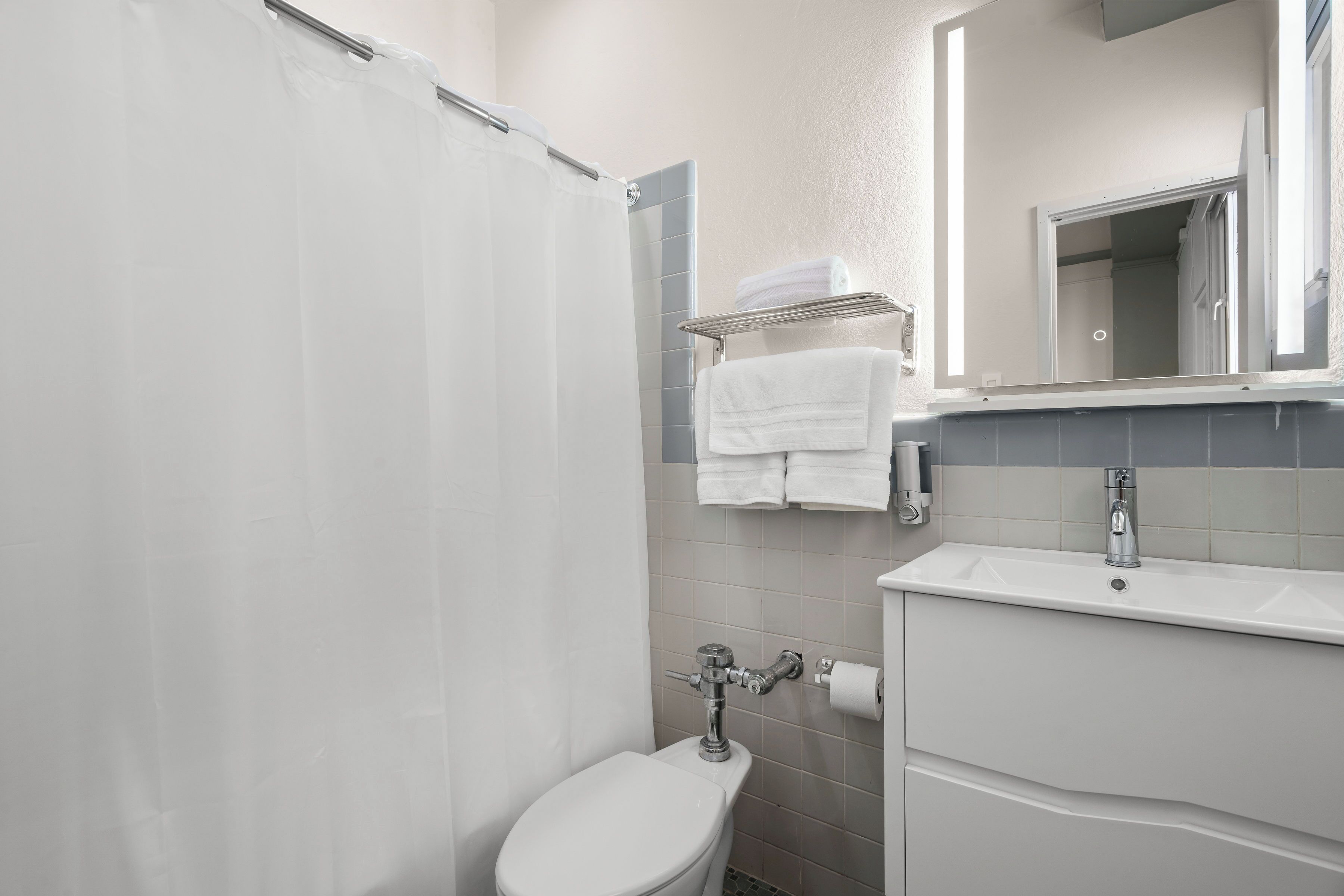 A bathroom with a toilet, a sink, a mirror, and a shower curtain.