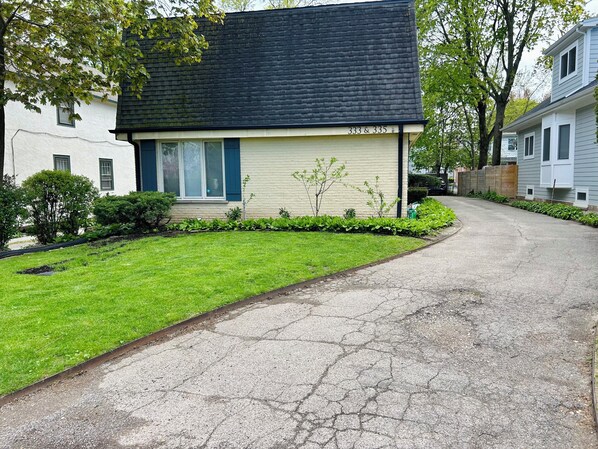 Una casa de dos pisos con techo negro y revestimiento color crema, ubicada en el número 333 y 335.
