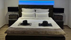 Ein modernes Schlafzimmer mit einem großen Bett, zwei Nachttischen und einer Deckenleuchte.