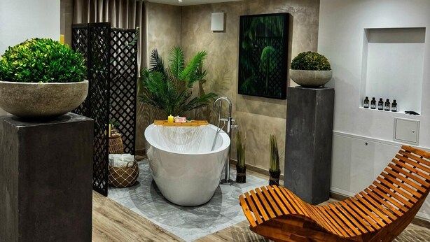 Ein modernes Badezimmer mit einer freistehenden Badewanne, einem Holz-Loungesessel und verschiedenen Pflanzen.