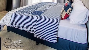 Een moderne slaapkamer met een bed, gordijnen, een plafondlamp en een kleine tafel.
