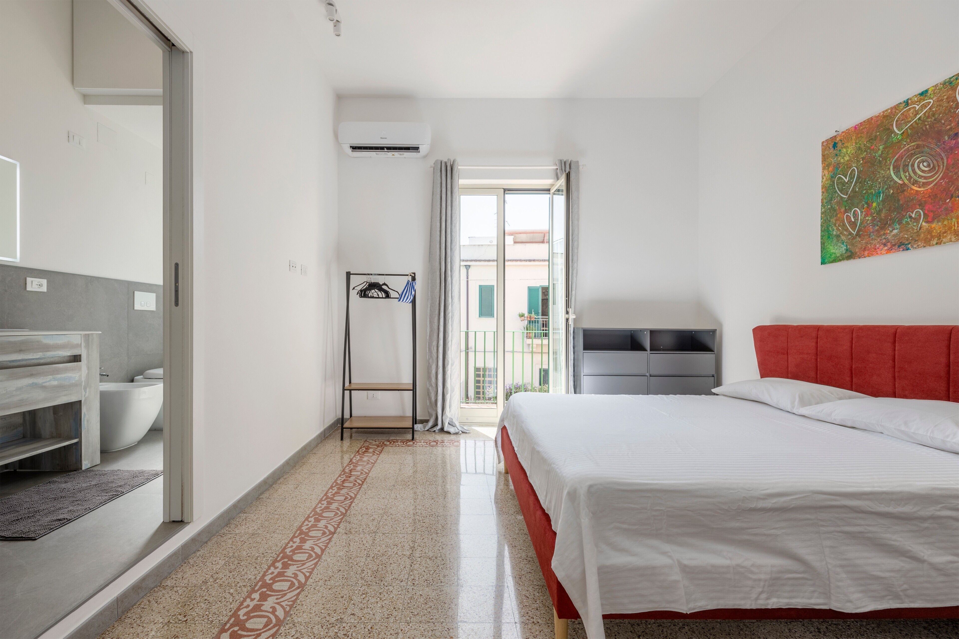 Habitación de hotel con cama, baño, ducha y vistas al exterior.