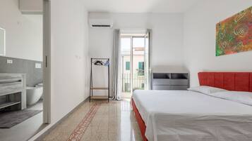 Habitación de hotel con cama, baño, ducha y vistas al exterior.