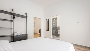 Een hotelkamer met een bed, een kledingkast, een spiegel en een douchehoek.