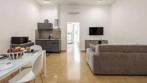 Een moderne woonkamer met een bank, een eettafel met stoelen, een keukenhoek en een televisie.