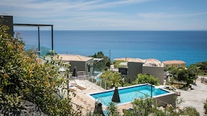 A resort with a swimming pool, lounge chairs, and a view of the sea. - Villa Mare ,  this brand new stylish villa boasts spectacular sea views! (Skala)