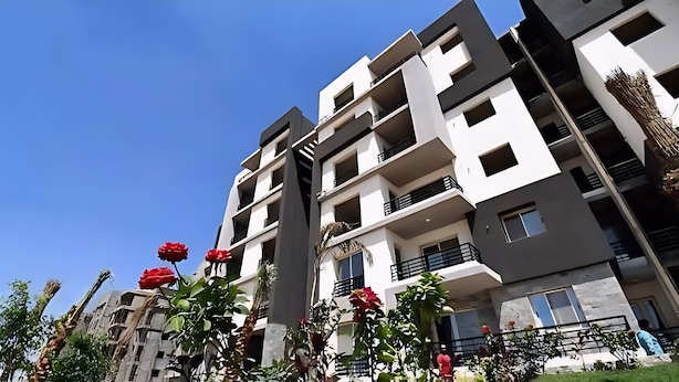 Ένα πολυώροφο κτίριο κατοικιών με μπαλκόνια, καθαρός ουρανός και λίγη βλάστηση.