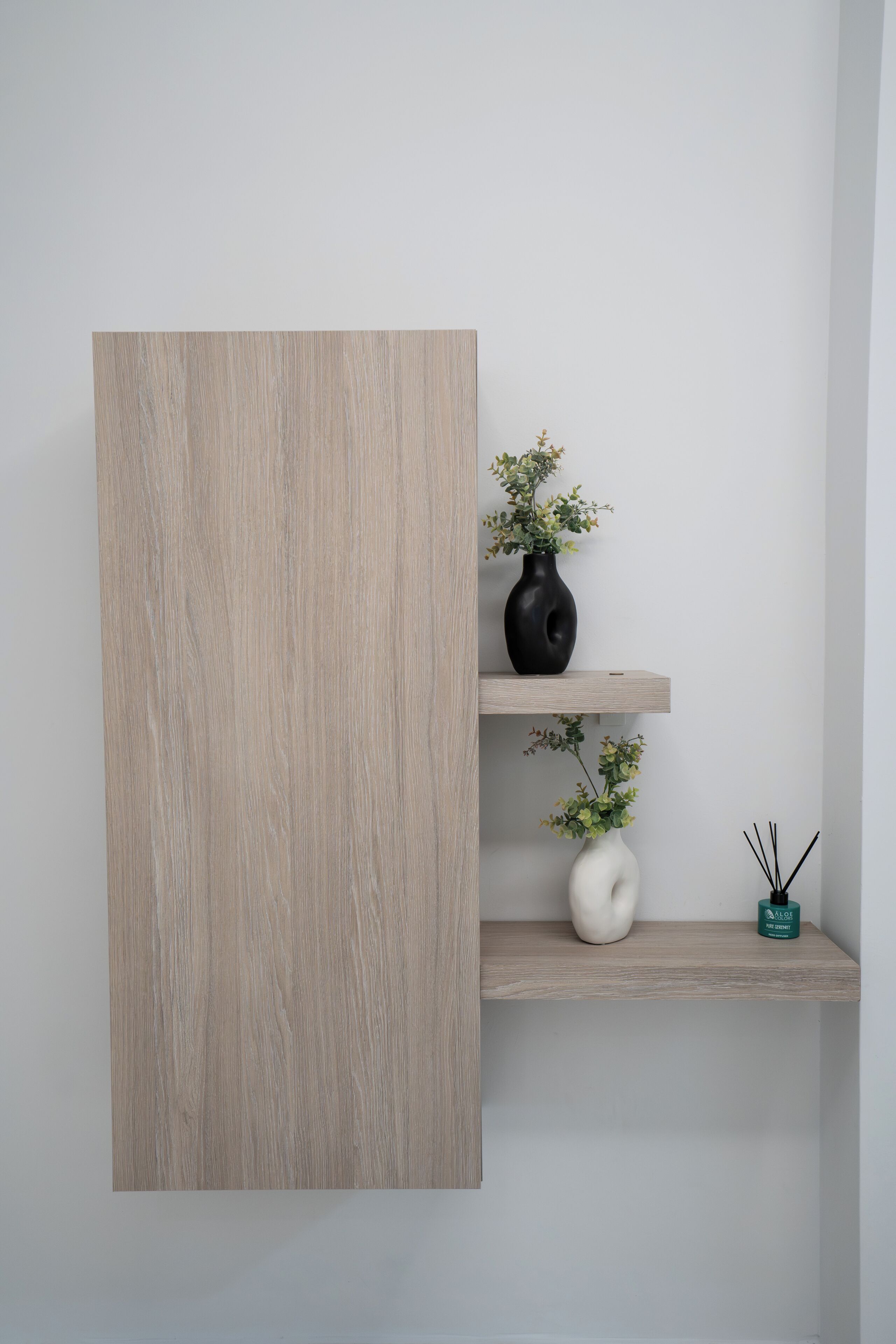 Una pared minimalista con un panel de madera clara y dos estantes.