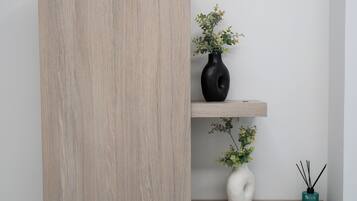 Una pared minimalista con un panel de madera clara y dos estantes.