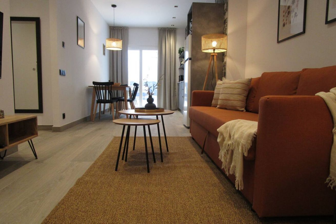 A modern living room with a sofa, coffee table, and chairs. There is a door, a window, and a lamp.