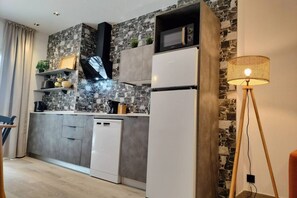 Eine moderne Küche mit Steinrückwand, weißen Geräten und Holzboden.
