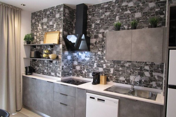 A modern kitchen with a stone backsplash, built-in appliances, and grey cabinetry.