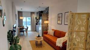 A modern living room with a sofa, a dining table, and a kitchen area in the background. - Travel Habitat Ruzafa Green House Patio (València)