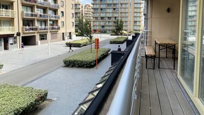 A residential building with multiple balconies, a pedestrian pathway, and a small plaza area with benches and greenery. - Apartment in Nieuwpoort-bad Near Beach (Nieuwpoort)