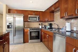 Una cocina con armarios de madera, electrodomésticos de acero inoxidable, microondas y salpicadero de azulejos.