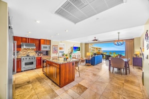 Una cocina moderna con una isla grande, un comedor con vistas y una sala de estar con vista a la piscina.