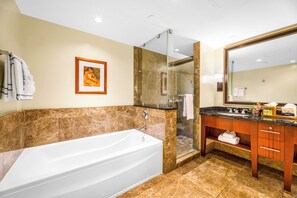 Une salle de bain avec une baignoire, une cabine de douche en verre, un meuble-lavabo avec un miroir et un tableau encadré au mur.
